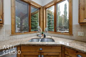 Kitchen with brown cabinets, light stone counters, and decorative backsplash