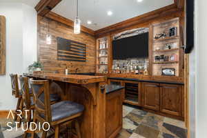 Indoor wet bar with open shelves, pendant lighting, dark stone finish floors, brown cabinetry, and wood counters