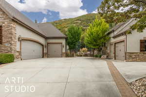 View of front of property with stone siding, a shingled roof, stucco siding, a mountain view, and concrete driveway