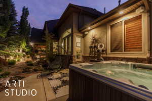 Property exterior at dusk with stucco siding, a hot tub, and a patio