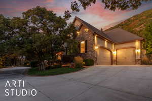 View of front of home featuring stone siding, concrete driveway, a shingled roof, and an attached garage