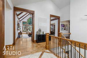 Hall featuring high vaulted ceiling, an upstairs landing, light wood-type flooring, and arched walkways