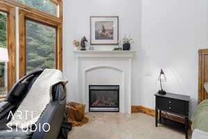 Carpeted living room with a glass covered fireplace and baseboards