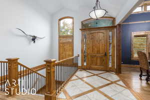 Foyer entrance with inlaid floor details and lofted ceiling