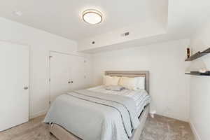 Bedroom with light colored carpet and a closet