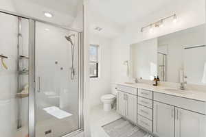 Full bathroom featuring double vanity, a stall shower, light tile patterned flooring, and recessed lighting