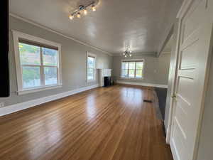 Unfurnished living room featuring a chandelier, dark wood-type flooring, ornamental molding, and a brick fireplace