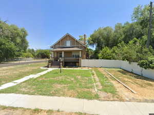Bungalow-style home with covered porch, a fenced backyard, and view of wooded area