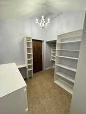 Spacious closet with light tile patterned flooring and a chandelier
