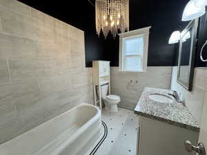 Bathroom with tile walls, vanity, a garden tub, and a chandelier
