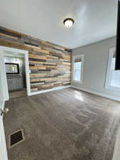 Carpeted spare room with wooden walls and baseboards