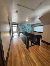 Corridor featuring an upstairs landing and wood finished floors