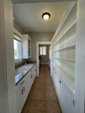 Kitchen with white cabinets, light stone countertops, plenty of natural light, and dark tile patterned floors