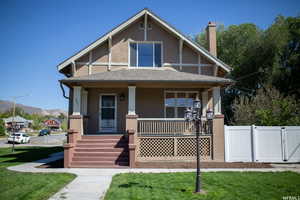 View of front of home with a porch, brick siding, a chimney, stucco siding, and a shingled roof