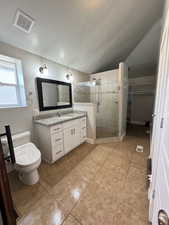 Bathroom with vanity, a shower stall, light tile patterned flooring, lofted ceiling, and a spacious closet