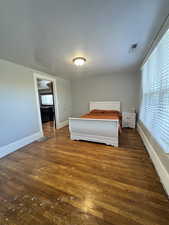 Unfurnished bedroom featuring dark wood-style flooring and baseboards