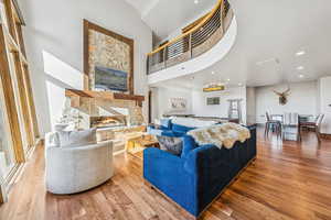 Living area with recessed lighting, wood finished floors, a fireplace, and a high ceiling