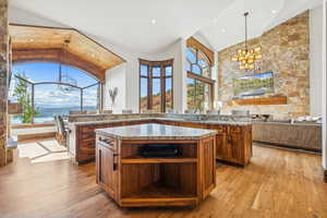 Kitchen featuring a chandelier, brown cabinets, pendant lighting, light wood-style floors, and light stone countertops