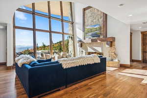 Living area featuring wood finished floors, a stone fireplace, floor to ceiling windows, and recessed lighting
