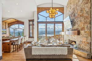 Living area with light wood finished floors, high vaulted ceiling, a fireplace, recessed lighting, and a chandelier