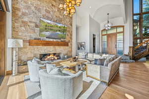 Living room with light wood finished floors, high vaulted ceiling, a fireplace, and stairway
