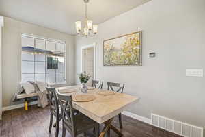 Dining space featuring dark wood finished floors and a chandelier