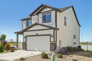 View of front of home featuring board and batten siding, brick siding, concrete driveway, and a garage