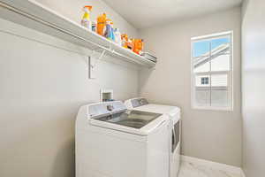 Laundry area featuring light marble finish floors and washer and dryer