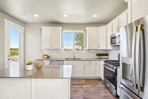 Kitchen featuring appliances with stainless steel finishes, white cabinets, backsplash, recessed lighting, and light wood finished floors