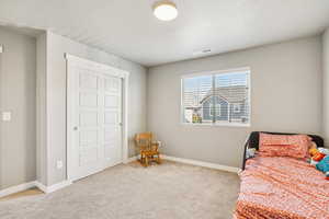 Bedroom with light carpet and a closet