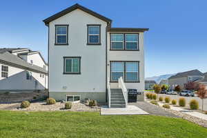 Back of house with a yard, stucco siding, a mountain view, and a residential view