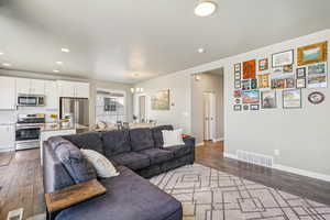 Living room with a chandelier, dark wood finished floors, and recessed lighting