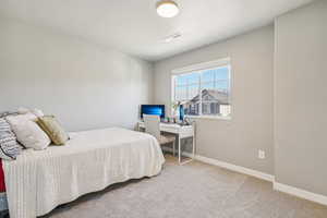 Carpeted bedroom with baseboards and a desk