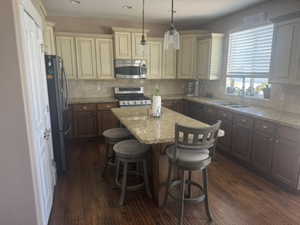 Kitchen featuring dark wood-style floors, tasteful backsplash, pendant lighting, stainless steel appliances, and recessed lighting