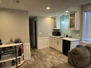 Kitchen featuring glass insert cabinets, wainscoting, light countertops, a decorative wall, and white cabinets