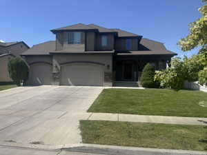 View of front of house with a porch, a front yard, driveway, and stucco siding