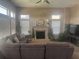 Living room with a fireplace with raised hearth, healthy amount of natural light, ceiling fan, carpet flooring, and recessed lighting