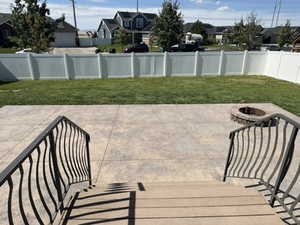 Fenced backyard featuring a patio area, a residential view, and an outdoor fire pit