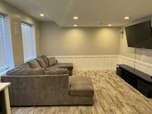 Living room with a decorative wall, wainscoting, recessed lighting, and wood finished floors