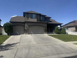 View of front of home with a porch, driveway, stucco siding, and stone siding