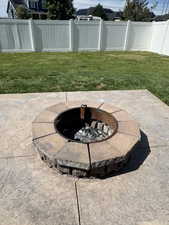 Fenced backyard featuring an outdoor fire pit and a patio