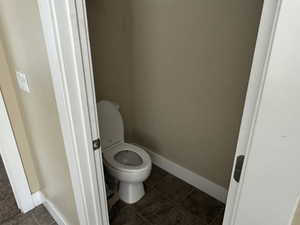 Bathroom with toilet and dark tile patterned flooring