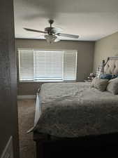 Bedroom with a textured ceiling, dark colored carpet, and ceiling fan