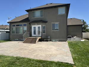 Rear view of property featuring a patio area, stucco siding, a fenced backyard, and french doors