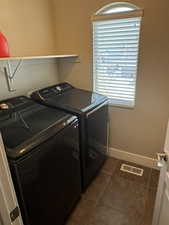 Washroom with dark tile patterned flooring and separate washer and dryer