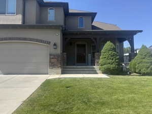 View of front of property with a porch, stucco siding, a garage, driveway, and a front yard