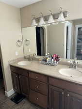 Full bathroom with double vanity and dark tile patterned floors