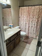 Full bath with vanity, light tile patterned floors, and curtained shower
