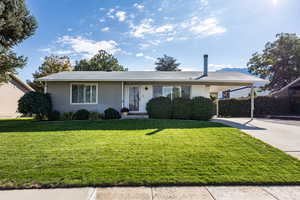 Ranch-style home featuring a front lawn, a carport, and concrete driveway