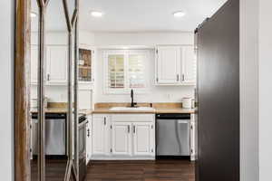 Kitchen with white cabinetry, appliances with stainless steel finishes, dark wood-type flooring, and recessed lighting